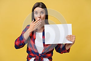 Amazement or surprised female with blank white panel, isolated on yellow background.