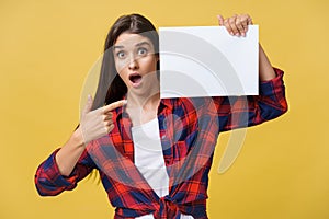 Amazement or surprised female with blank white panel, isolated on yellow background.