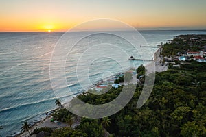 Amazing aerial sunset view of Caribbean tropical paradise beach with tourist resort, sea and blue sky with sun, outdoor travel