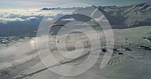 Amazing aerial video of paraplane at snow mountains. Close-up drone of paraglide winter`s mountains