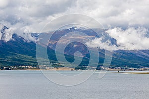 Amazing Altai natural landscape, calm lake with emerald water, surrounded by incredible mountain ice peaks with a gloomy, cloudy