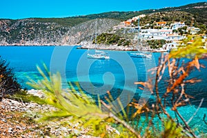 Amazing Assos village, Kefalonia. Greece. White cruise yachts staying at anchor in beautiful emerald green colored