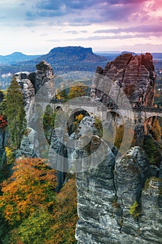 Amazing autumn landscape in Saxon Switzerland National Park. View of exposed sandstone rocks and forest hills at sunset. Germany.