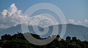 Amazing autumn panorama with mountains covered with snow and forest against the background of blue sky and clouds. Mount Everest,