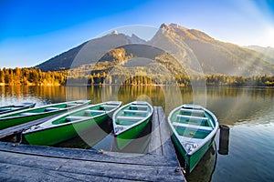 Amazing autumn scenery on Hintersee lake with boats moored on wooden pier, Bavaria, Germany