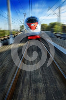 Amazing beautiful impressive front view on moving white red blue beautiful high speed passenger train in motion blur. High speed