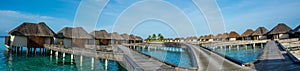 Amazing beautiful tropical beach panorama of water bungalos with bridge near the ocean at Maldives