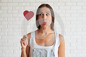 Amazing beautiful woman holding red paper heart and look at it