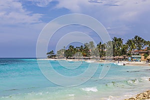 Amazing beauty Atlantic ocean white sand beach of Aruba Island. Turquoise sea water and green palm trees and blue sky background.