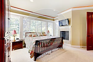 Amazing bedroom interior with fireplace and cherrywood furniture set.