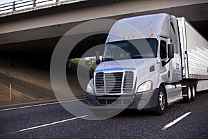 Amazing big rig grey semi truck with semi trailer driving under