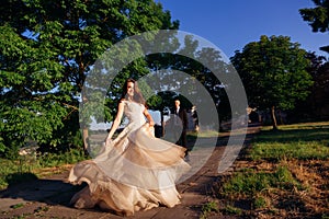 Amazing bride whirls her beige dress while standing on the path