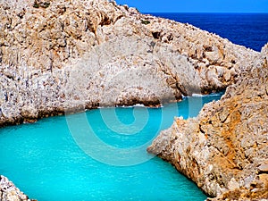 Amazing bright blue water in a secluded cove with orange cliffs surrounding it - Crete, Greece