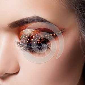 Amazing Bright eye makeup with a arrow with rhinestones. Brown and gold tones, colored eyeshadow