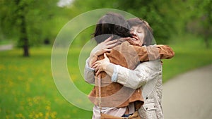 Amazing Brunette is Hugging Her Mother with Love and Tenderness in the Park. Portrait of Adult Daughter and Her Mom