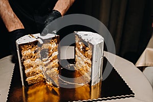 Amazing Cakes. A black-gloved chef is slicing a chocolate wedding cake. The wedding Cake is delicious inside on a black background