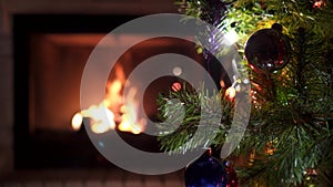 Amazing Christmas tree blinking colorful lights garland near fireplace with burning fire log