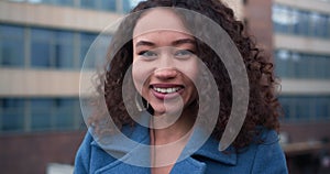 Amazing close-up portrait of happy beautiful 20-25 mixed race student woman posing at city building slow motion.