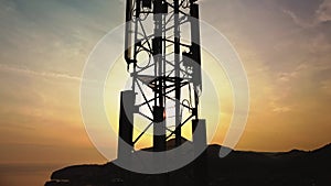 Amazing closeup sunset drone view of silhouette of cell tower. Wireless connection. Spectacular view of cellular tower with mounta