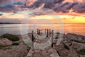 Amazing colorful sunrise over the sea, rocks and stone stairs, scenic seascape, Cavo Greko, Ayia Napa, Cyprus