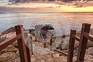 Amazing colorful sunrise over the sea, rocks and stone stairs, scenic seascape, Cavo Greko, Ayia Napa, Cyprus photo