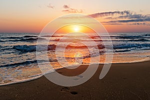 Amazing colorful sunrise at sea, footprints in the sand