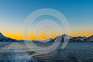 Amazing colorful sunset over Norwegian sea seen from small cruise ship MS Lofoten of Hurtigruten on clear winter day