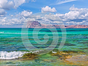 Amazing crystal clear blue water on a paradise beach - small wave - rocky island in the background