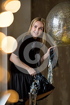 Amazing cute lady celebrating new year birthday party, posing in gold shine background and throwing colorful confetti with silver