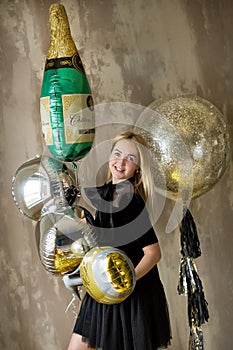 Amazing cute lady celebrating new year birthday party, posing in gold shine background and throwing colorful confetti with silver