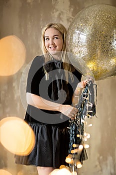 Amazing cute lady celebrating new year birthday party, posing in gold shine background and throwing colorful confetti with silver