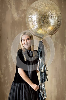 Amazing cute lady celebrating new year birthday party, posing in gold shine background and throwing colorful confetti with silver