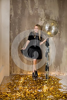 Amazing cute lady celebrating new year birthday party, posing in gold shine background and throwing colorful confetti with silver