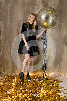 Amazing cute lady celebrating new year birthday party, posing in gold shine background and throwing colorful confetti with silver