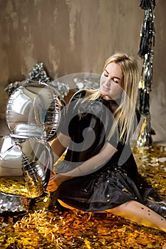 Amazing cute lady celebrating new year birthday party, posing in gold shine background and throwing colorful confetti with silver