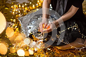 Amazing cute lady celebrating new year birthday party, posing in gold shine background and throwing colorful confetti with silver