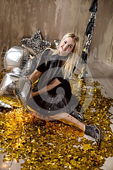 Amazing cute lady celebrating new year birthday party, posing in gold shine background and throwing colorful confetti with silver