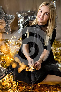 Amazing cute lady celebrating new year birthday party, posing in gold shine background and throwing colorful confetti with silver