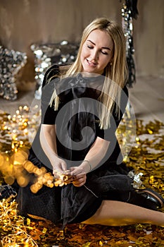 Amazing cute lady celebrating new year birthday party, posing in gold shine background and throwing colorful confetti with silver