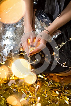 Amazing cute lady celebrating new year birthday party, posing in gold shine background and throwing colorful confetti with silver