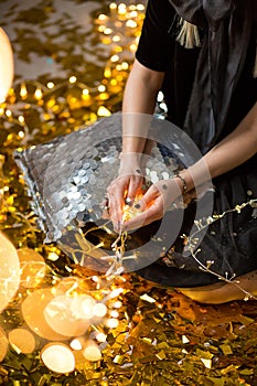 Amazing cute lady celebrating new year birthday party, posing in gold shine background and throwing colorful confetti with silver