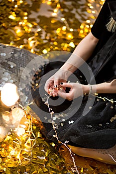 Amazing cute lady celebrating new year birthday party, posing in gold shine background and throwing colorful confetti with silver