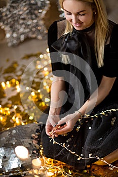 Amazing cute lady celebrating new year birthday party, posing in gold shine background and throwing colorful confetti with silver