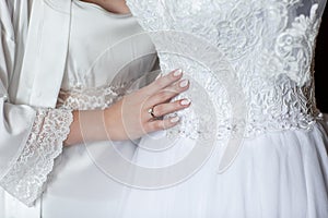 Amazing dress. beautiful young woman in silk bathrobe touching her wedding dress. Detail of an elegant white wedding dress