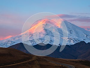 Amazing fiery dawn on a snowy mountain. Sunlight in the mountains. Big glacier on top in pink light. Scenic mountain landscape