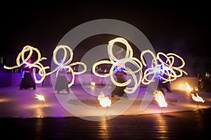 Amazing fire show dance. Fire dancers in beautiful costumes playing with colorful flames