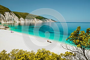 Amazing Fteri beach lagoon, Cephalonia Kefalonia, Greece. Tourists under umbrella relax near clear blue emerald turquise