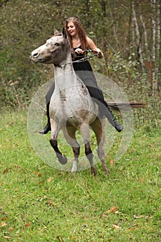 Amazing girl with long hair riding a horse