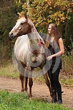 Amazing girl standing next to the appaloosa horse