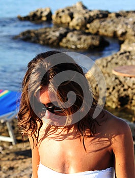 Amazing girl with sunglasses in a white swimsuit  walking on the rocky beach. Apulia, Salento, Italy